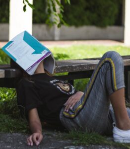 Woman has fallen asleep while studying and has a book over her face.